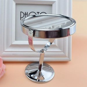 Detalle de espejo de maquillaje en metal plateado con marco redondo y base estable