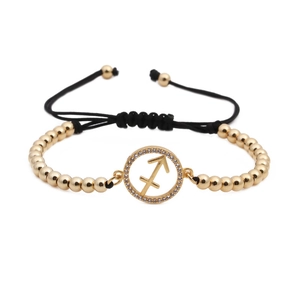 Macro detail of Sagittarius zodiac gold-plated charm with sparkling zircon and black rope