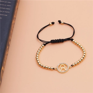 Detailed view of Taurus zodiac gold bracelet with black braided rope and zircon stones