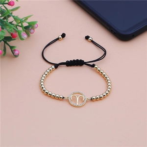 Detail of gold Aries zodiac charm bracelet with cubic zirconia and black woven rope strap