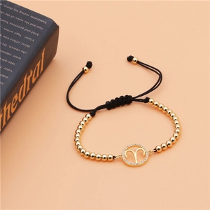 Detail of Aries zodiac charm with micro-pave crystals on a gold beaded adjustable bracelet