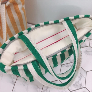Detailed interior of green striped canvas tote bag showing zipper and spacious capacity
