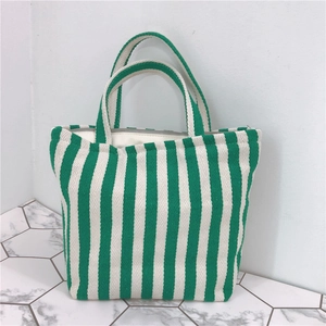 Detail of green and white striped canvas handbag with thick handles and inner lining