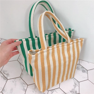 Detailed view of striped canvas tote bags in yellow and green with reinforced handles