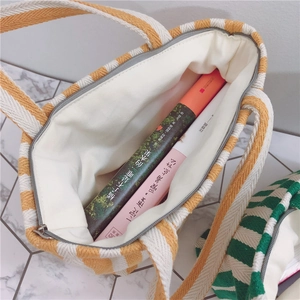 Top view of striped knit handbag showing spacious interior with zipper and books