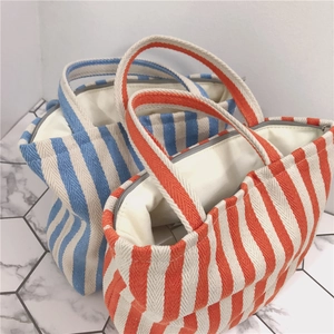 Detailed view of canvas tote bags with striped patterns and secure zipper closures