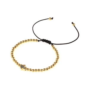Golden Hamsa Hand bracelet with blue stones and adjustable black woven cord on white base
