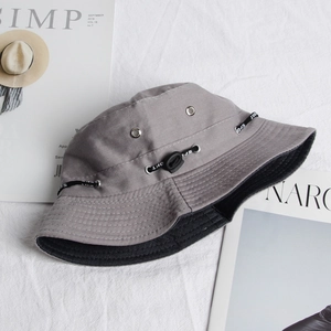 Detail of grey canvas bucket hat featuring breathable metal eyelets and a Sport cord strap