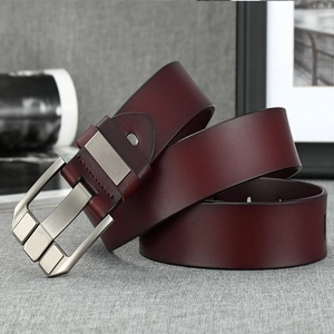 Detail of red-brown genuine leather belt with brushed metal pin buckle on fabric