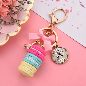 Macaron cake keychain with pink bow and golden Eiffel Tower charm on pink background