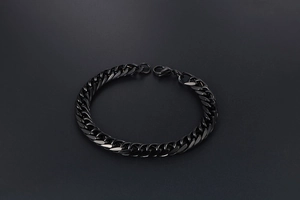 Detail of a sleek black stainless steel Cuban link bracelet with a lobster clasp