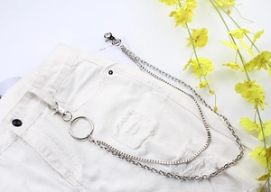 Detail of silver multi-layered metal trousers chain styled on white denim shorts