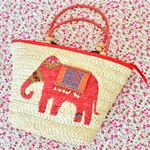 Detail of straw tote bag with red elephant embroidery and wooden bead accents
