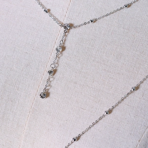 Close-up of silver body chain necklace with y-shaped crystal fringe and beaded design
