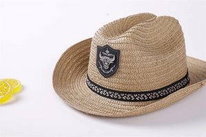 Close-up of woven straw cowboy hat featuring a metallic bull head crest on the black band