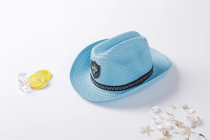 Detail of light blue straw cowboy hat with leather badge and black vintage ribbon band