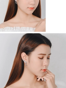 Detail view of silver butterfly tassel earrings with blue zircon crystals on a model
