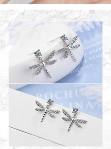 Macro shot of silver dragonfly earrings with intricate sparkling zircon stone inlay