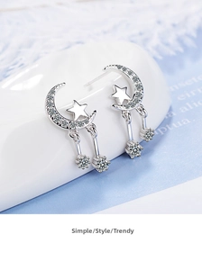 Detailed macro shot of silver crescent moon and star earrings with pavé rhinestones