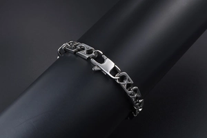 Macro detail of silver mesh bracelet with X-shaped links and spring clasp on black surface
