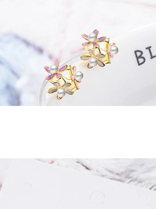 Detail of floral earrings with purple and pink enamel petals and white pearls on gold metal