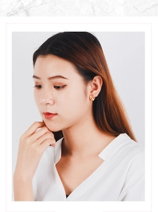 Close-up of elegant gold flower stud earrings worn by a model against white background