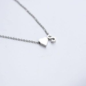 Polished silver stainless steel heart necklace with letter S pendant on white background