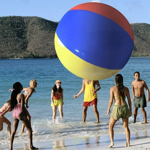 People playing with a giant colorful inflatable PVC beach ball in the shallow ocean water