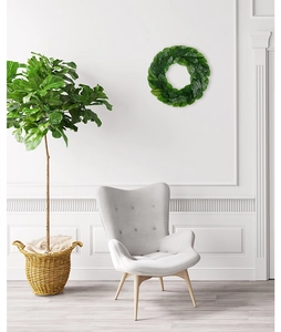 Close-up of lifelike magnolia leaf wreath hanging on white wall in modern living room