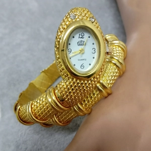 Close-up of gold snake bracelet watch with sparkling crystal eyes and textured metal band