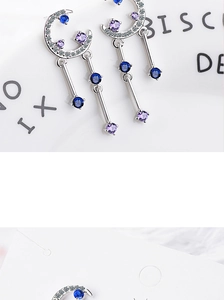 Macro view of silver moon tassel earrings with sparkling blue and purple zircons