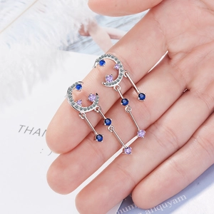 Star and moon dangle earrings with blue and purple zircons on a hand-held display