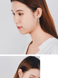 Detail view of crescent moon tassel earrings with sparkling blue and purple zircons