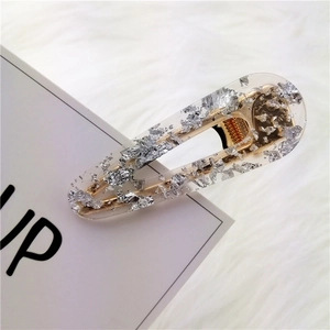 Detail of a resin hair clip with silver foil flakes on a soft white plush background