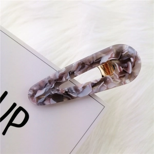 Macro view of teardrop acetate hair clip with purple marble texture on gold metal clip