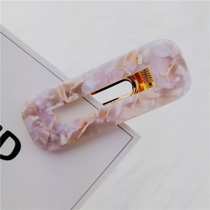 Macro view of rectangular acetate hair clip featuring purple marble texture and gold metal spring