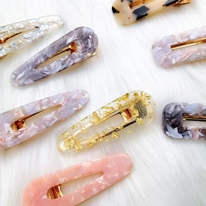 Close-up of geometric acetate hair clips in marble and gold foil patterns on white fur