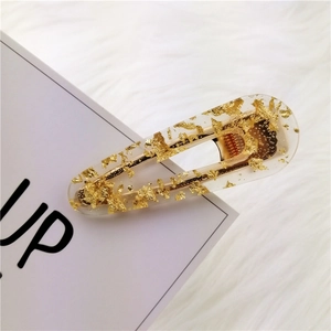 Detailed macro view of an acetate hair clip with golden foil flakes and a metal base