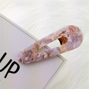 Detailed macro view of acetate marble patterned water drop hair clip on white card