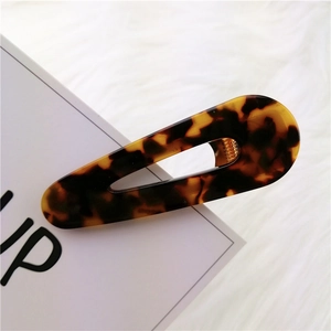 Detailed view of tortoiseshell acetate drop-shaped hair clip on soft white faux fur background