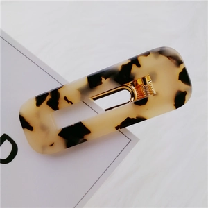 Detail shot of a rectangular tortoiseshell acetate hair clip with golden metal spring clip