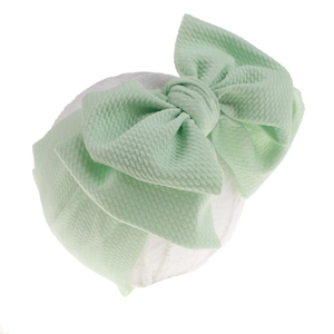 Detail of mint green waffle fabric baby headband featuring a large bow on a model head