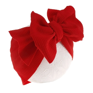 Macro view of a vibrant red textured fabric bow headband for infants and babies.