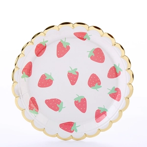 Detail of white paper plate with pink strawberry pattern and golden wavy scalloped edge