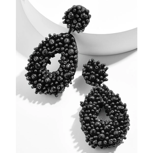 Macro shot of handmade black seed bead teardrop earrings with a detailed woven texture