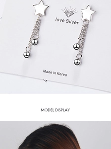 Detail of silver star earrings featuring long tassel chains and polished beads