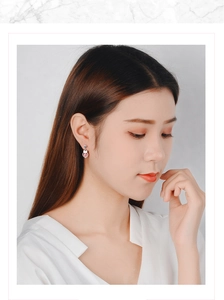 Close-up of model wearing silver hoop earrings with a round pink strawberry quartz stone
