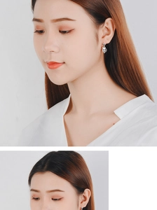 Close-up detail of silver geometric drop earrings with white round bead on female ear
