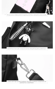 Detail view of black oxford backpack showing side pocket, bear charm and silver metal hook