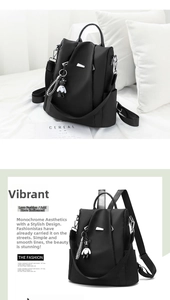 Close-up of black oxford backpack featuring silver metal zippers and a cute bear keychain charm